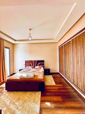 A bedroom with a large bed, a ceiling light, and a view of the outside through a window. - Anza Family Retreat – 4 Bedrooms & Spacious Lounge (Agadir)