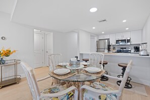 A modern kitchen with white cabinets, a stainless steel refrigerator, and a coffee machine. - Estero Island Yacht & Racquet 212-dockside Paradise (Fort Myers Beach)
