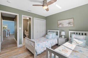A bedroom with two beds, a ceiling fan, and a painting on the wall. - Canal Paradise Retreat (Fort Myers Beach)