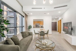 Een modern appartement met een zithoek, eethoek, kitchenette en een aan de muur bevestigde televisie.