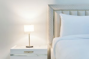 A neatly made bed with a headboard, a bedside table with a lamp, and a drawer. - FIRST CLASS | 2BR | Burj View | Premium City Stay (Dubai)