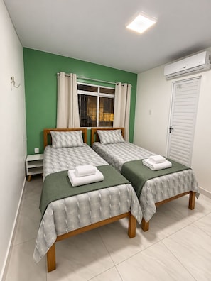 A bedroom with two beds, a window with curtains, a white door, and an air conditioning unit. - Casa verde com Wi-Fi 700MB e ãgua quente (Belém)