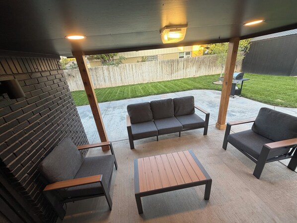 Une terrasse extérieure avec un canapé, deux fauteuils et une table.