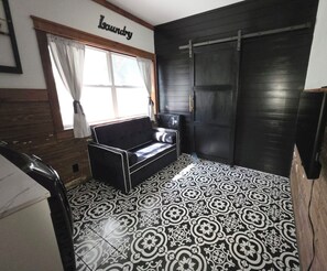 A room with a sofa, a window with curtains, a door, and patterned floor tiles. - Casa Grande +Boat Parking + Fire Pit + Coffee/Wine Bar (Belton)