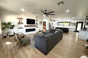 A modern living room with a grey sofa, wooden floor, and a flat-screen TV mounted on the wall. - Casa Grande +Boat Parking + Fire Pit + Coffee/Wine Bar (Belton)