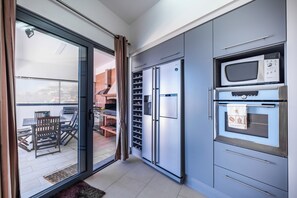 A modern kitchen with a built-in refrigerator, microwave, and oven. - Villa Rodrigues (Ponta do Sol)