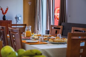 A breakfast setting with a table set for two, including plates, glasses, and a variety of food items. - Villa Rodrigues (Ponta do Sol)