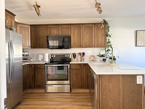 A modern kitchen with wooden cabinets, stainless steel appliances, and a white countertop. - The ultimate lake getaway awaits! (Sylvan Lake)