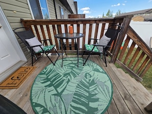 A wooden deck with two chairs and a small table, a doormat, and a view of the house. - The ultimate lake getaway awaits! (Sylvan Lake)