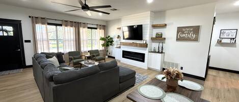 A modern living room with a sectional sofa, a flat-screen TV, and a fireplace.