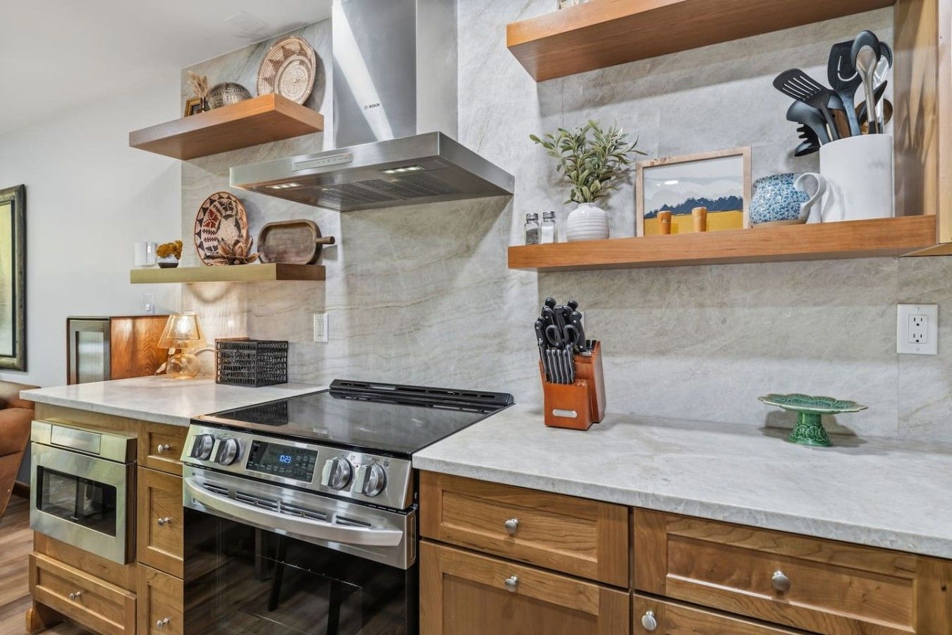 Una cucina con piano cottura in acciaio inossidabile, mobili in legno e ripiani in marmo.