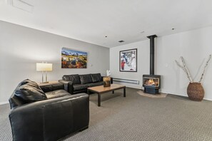 Una sala de estar moderna con un sofá, una mesa de centro, una chimenea y dos cuadros colgados en la pared.