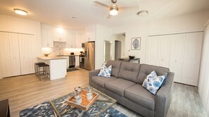 A modern living room with a gray sofa, a coffee table, and a kitchen area in the background. - Sonoma 2BR Condo w/ AC & Kitchen -- Chardonnay (Sonoma)