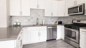 A modern kitchen with white cabinets, stainless steel appliances, and a marble backsplash. - Sonoma 2BR Condo w/ AC & Kitchen -- Chardonnay (Sonoma)