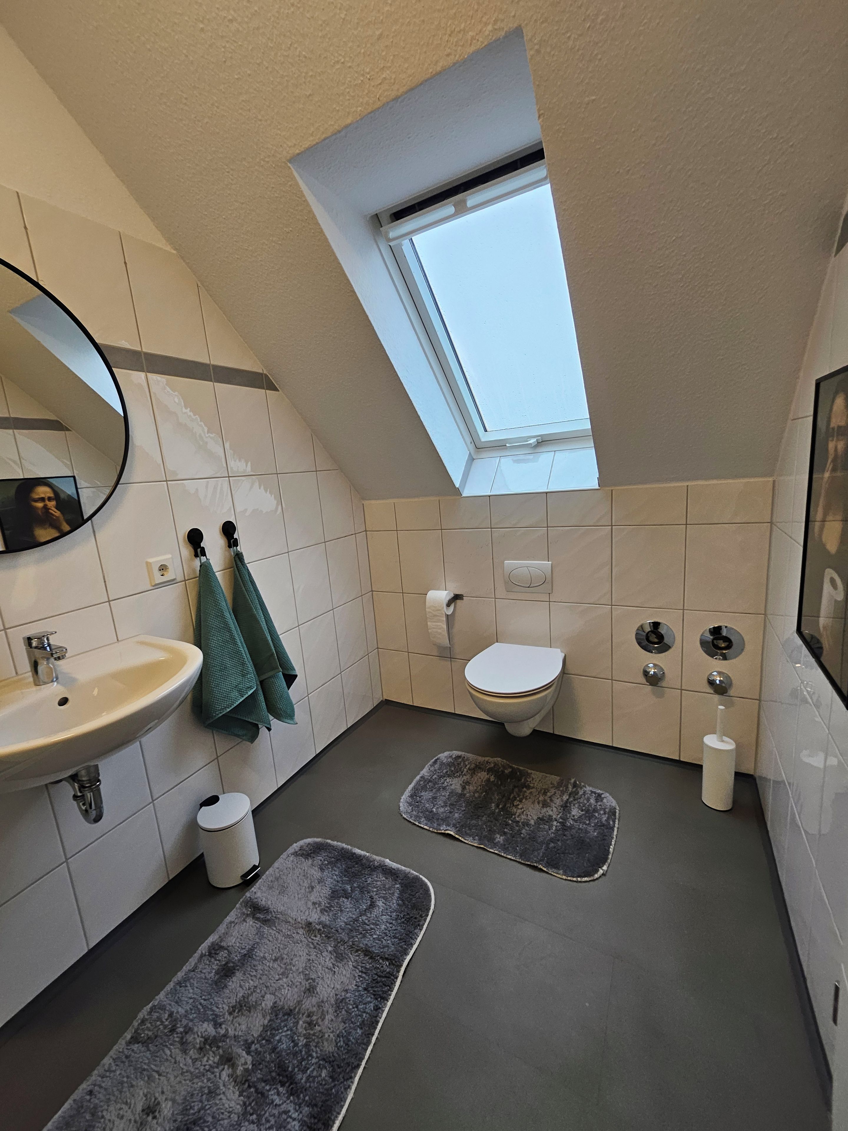 Un baño moderno con tragaluz, lavabo, inodoro y bidé.