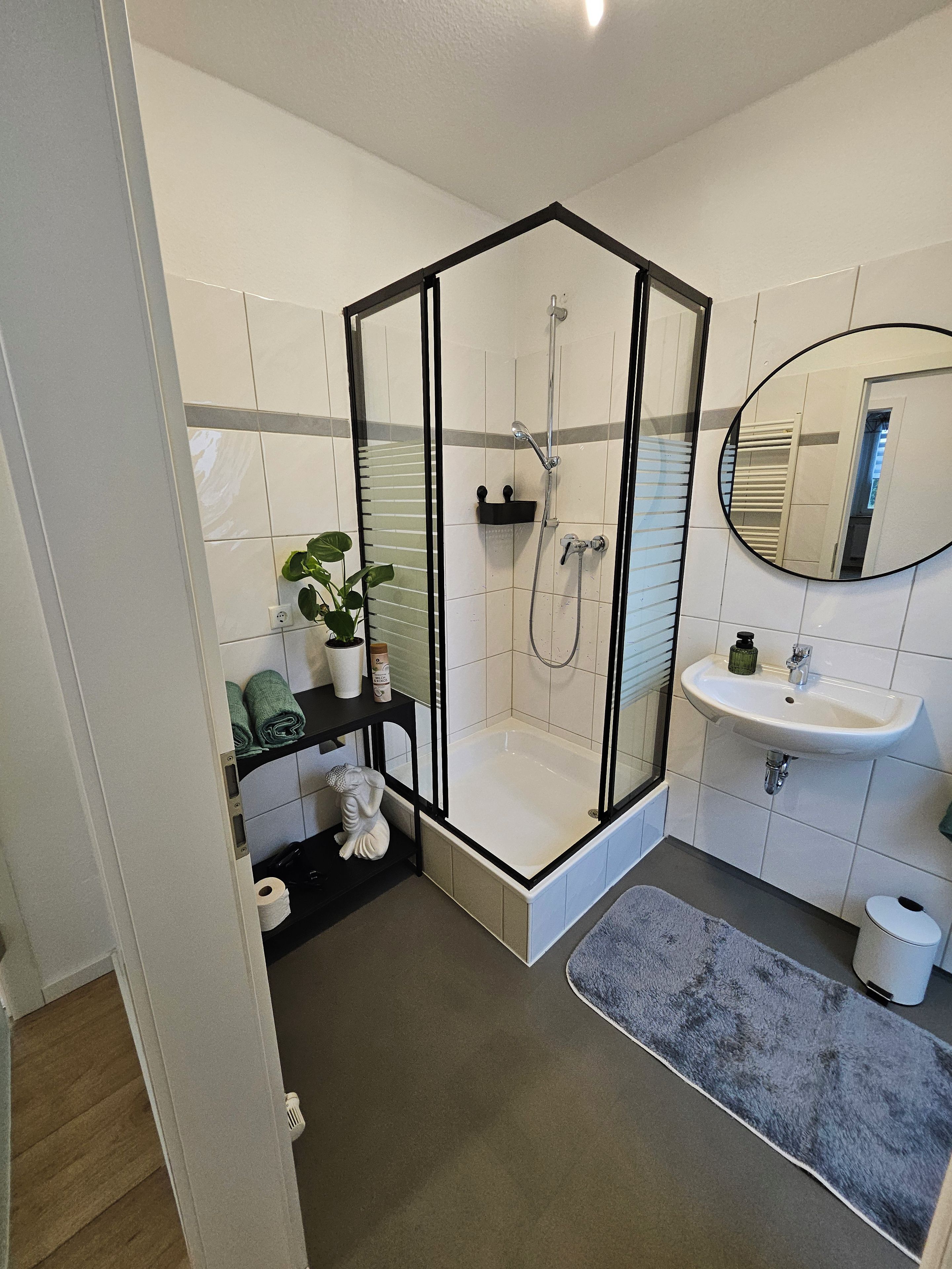 Een moderne badkamer met een douchecabine van glas, een wastafel en een spiegel.