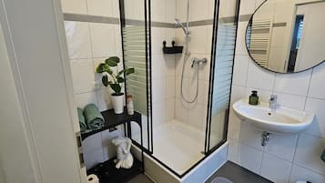 Een moderne badkamer met een douchecabine van glas, een wastafel en een spiegel.