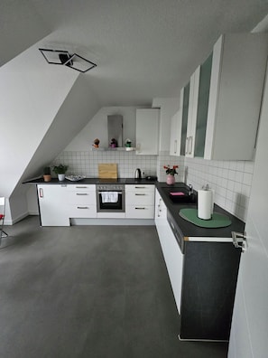 Una cocina moderna con armarios blancos, encimera negra y salpicadero de azulejos.