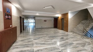 Un pasillo espacioso con suelo de mármol, una escalera y un cartel con los números de los apartamentos.