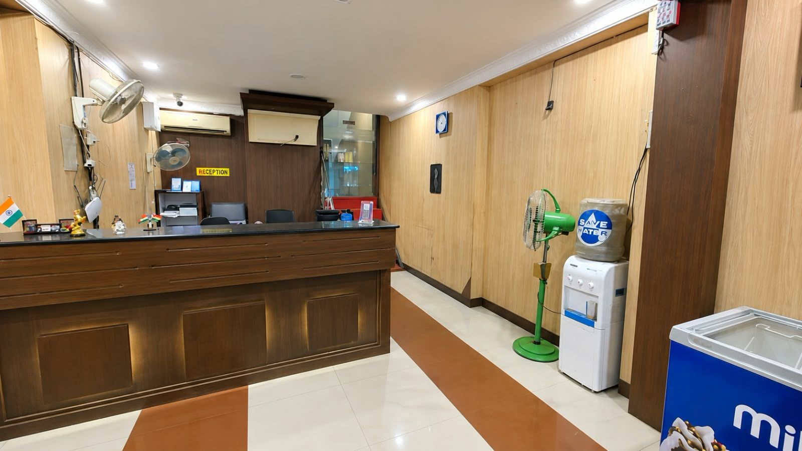 A reception area with a wooden counter, a reception desk, a water dispenser, and a clock on the wall.