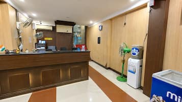 A reception area with a wooden counter, a reception desk, a water dispenser, and a clock on the wall.