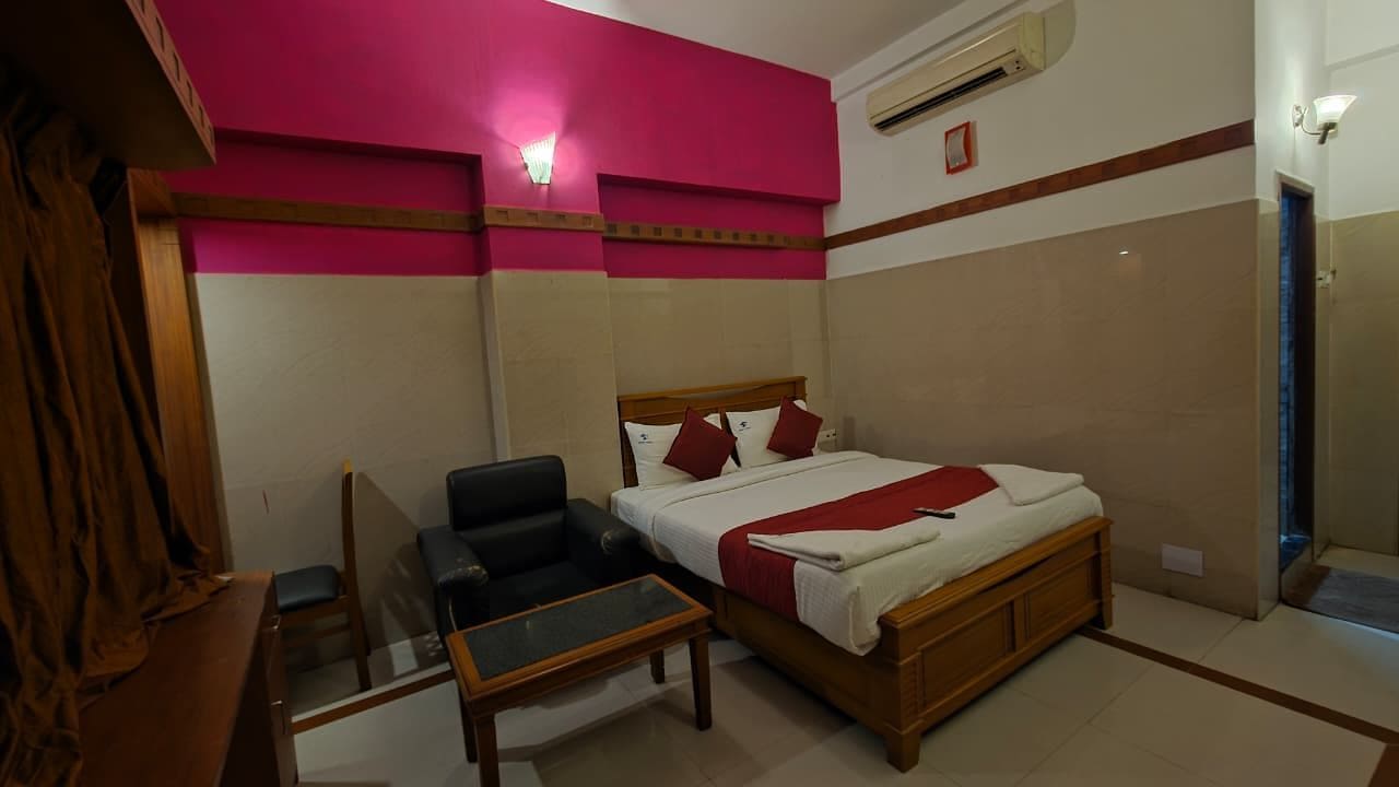 Une chambre d’hôtel avec un lit, une chaise, une petite table et un miroir.