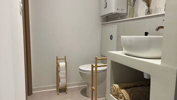 A bathroom with a toilet, a white sink, and a towel rack.