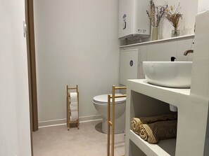 A bathroom with a toilet, a white sink, and a towel rack. - (Avignon)