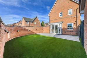 A residential property with a brick exterior, a well-maintained lawn, and a covered patio area. - 2-Bed Home with Parking Near Trent Bridge (Nottingham)