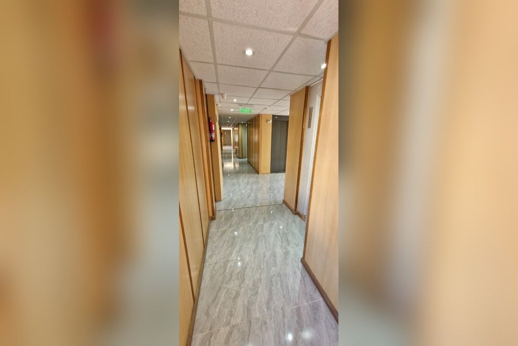 Un couloir doté d’un sol en marbre, de lambris en bois sur les murs et d’un plafond pourvu d’un éclairage encastré.