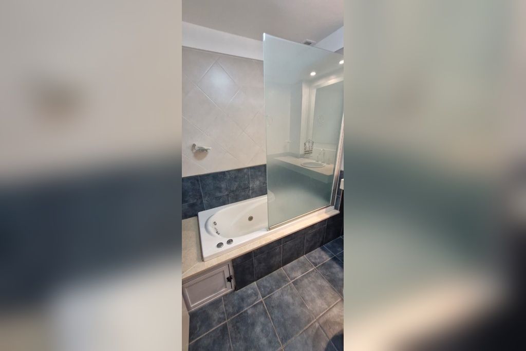 Un bagno moderno con doccia vetrata, vasca e lavabo con specchio.
