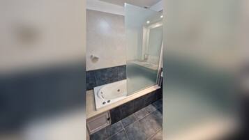 Un bagno moderno con doccia vetrata, vasca e lavabo con specchio.