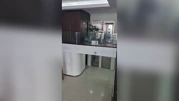 Un área de recepción con mostrador, escalera y una planta.