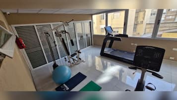 Un gimnasio con cinta de correr, pelota de ejercicios y máquinas de pesas.