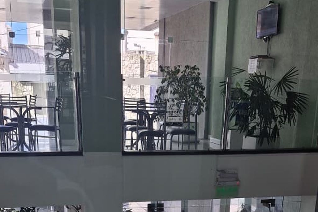 Una stanza con una grande finestra, una sedia, un tavolo e una pianta in vaso.