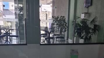 Una stanza con una grande finestra, una sedia, un tavolo e una pianta in vaso.
