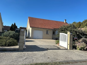A two-story house with a red-tiled roof, a white garage door, and a gated driveway. - The Lovers' Retreat: a cozy home where you can relax in the garden or enjoy an evening by the fire (Romilly-sur-Andelle)