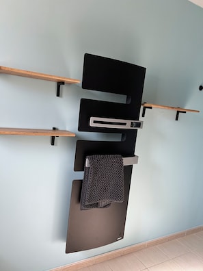 A wall-mounted black shelf unit with a wooden handle and a textured mat. - The Lovers' Retreat: a cozy home where you can relax in the garden or enjoy an evening by the fire (Romilly-sur-Andelle)
