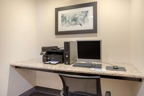Ein Arbeitsplatz mit Schreibtischcomputer, Drucker und Tastatur.