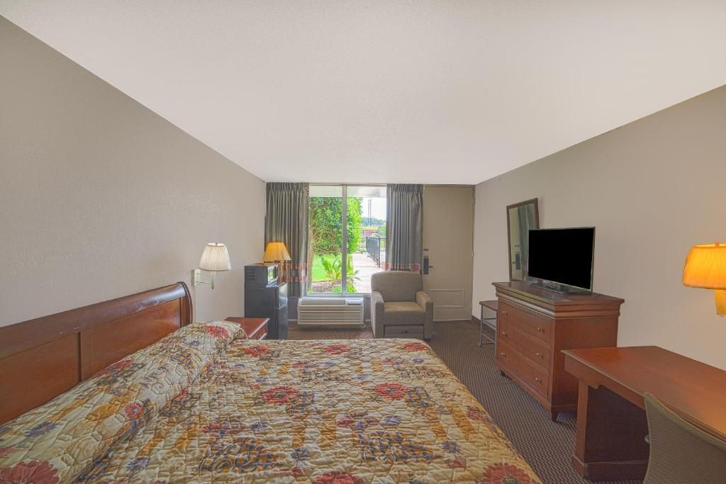 A hotel room with a bed, a television, a desk, and a chair.