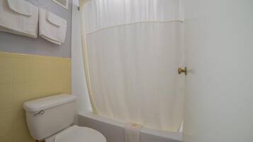 A bathroom with a toilet, a bathtub, and a shower curtain.