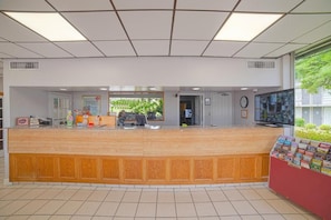 A reception area with a wooden counter, a clock, and a television.