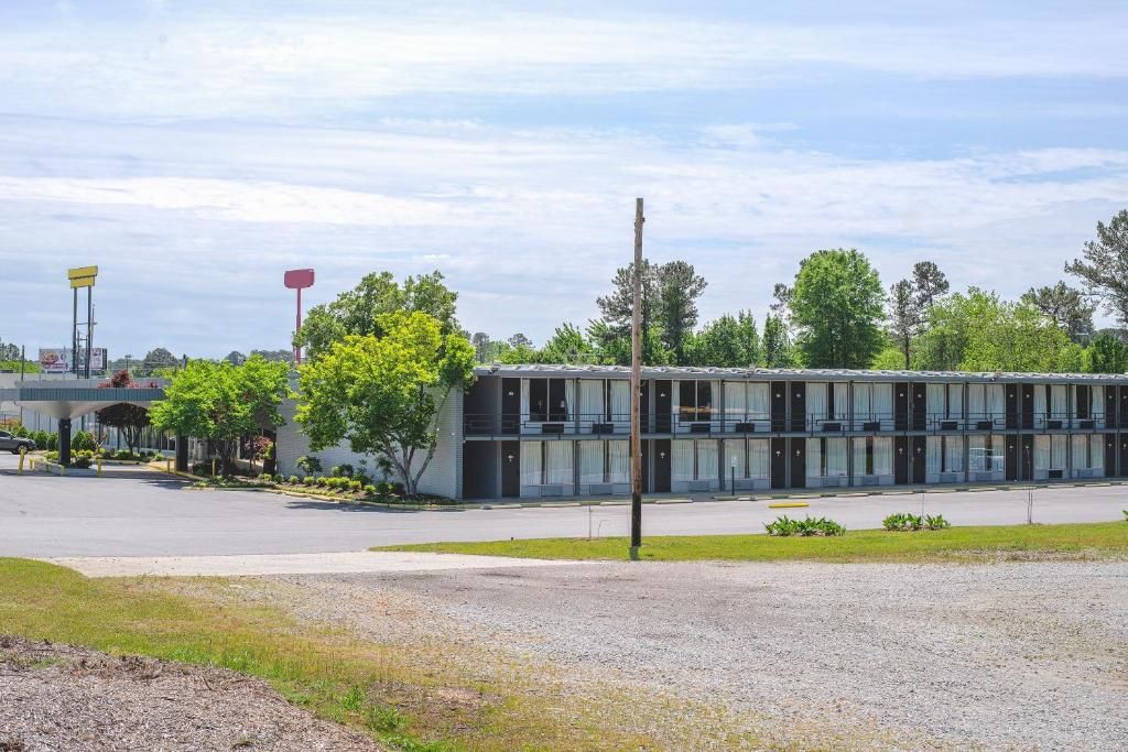 Un motel doté d’un parking, d’une allée couverte et d’un bâtiment avec de nombreuses fenêtres.