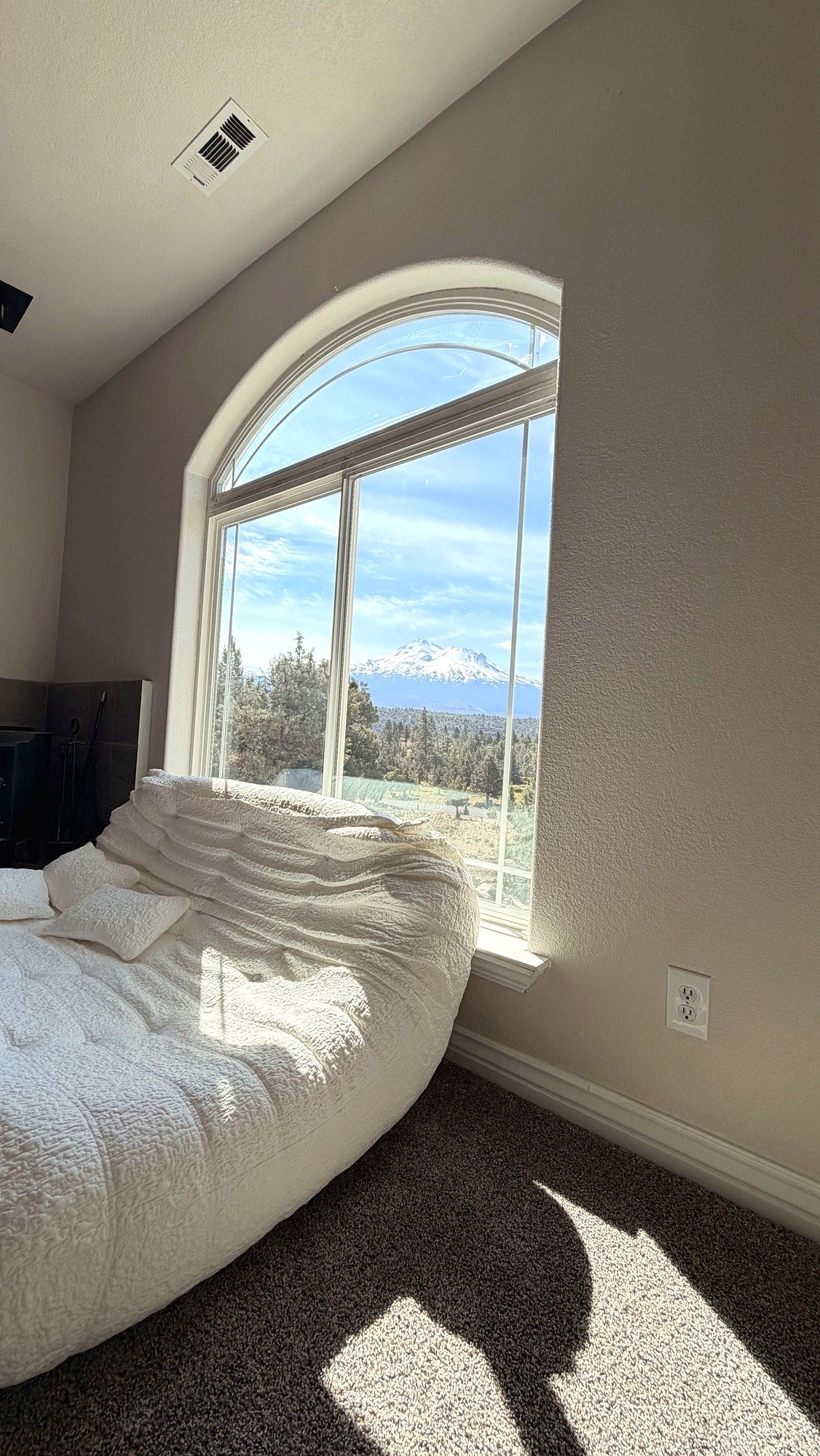 Una camera da letto con un'ampia finestra ad arco, un letto e vista su una montagna.