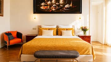 A modern bedroom with a large bed, a bench, a chair, and a painting above the bed.