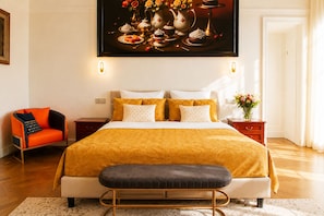 Une chambre à coucher moderne avec un grand lit, un banc, une chaise et un tableau au-dessus du lit.