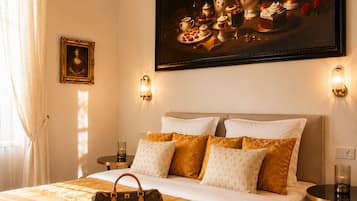 Une chambre d’hôtel avec un grand lit, un tableau de fleurs, un cadre avec une photo accroché au mur et un sac à main posé sur le lit.