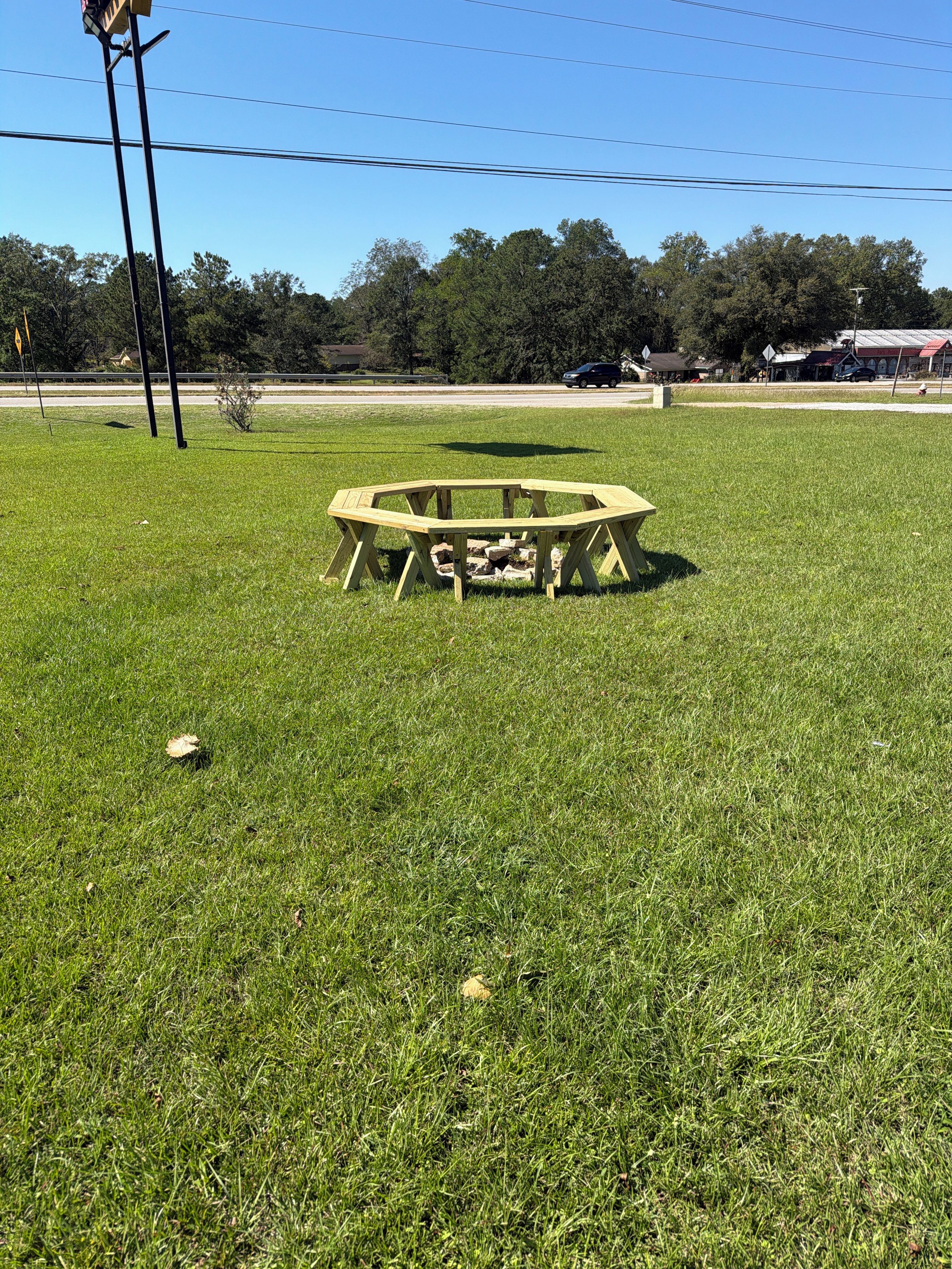 A wooden picnic table in a grassy field with a clear sky.