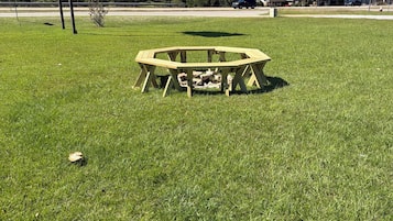 A wooden picnic table in a grassy field with a clear sky.