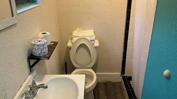 A bathroom with a white sink, toilet, and a small window.